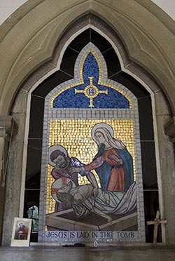Mosaic Panel showng Jesus being laid in the tomb, set in a recess with devotional objects.