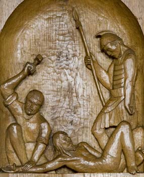 Jesus is nailed to the cross, carved in wood.