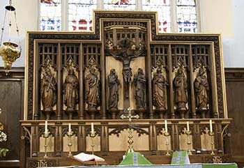 Carved wooden reredos with crucifixion and saints.