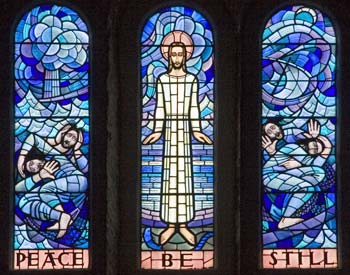 Three light window by John Petts. with text 'Peace Be Still'.